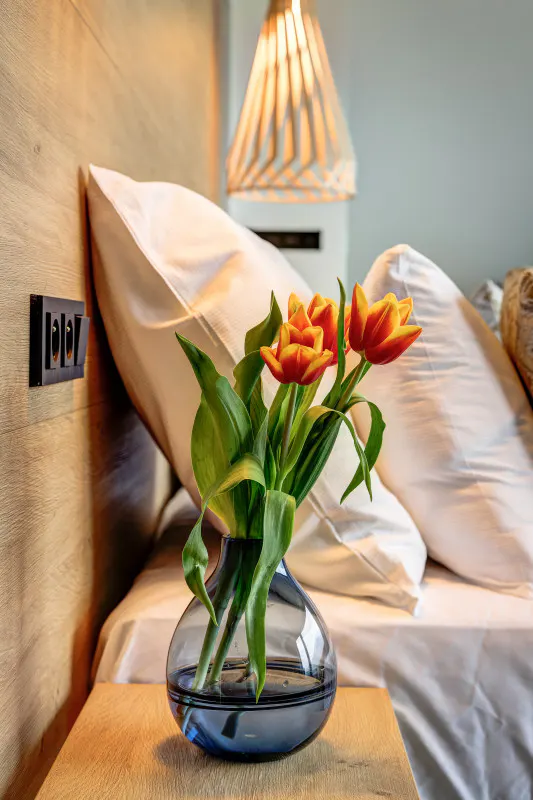 Váza s oranžovými tulipány na nočním stolku hotelového pokoje